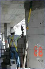 Masonry worker harnessed to building with safety straps